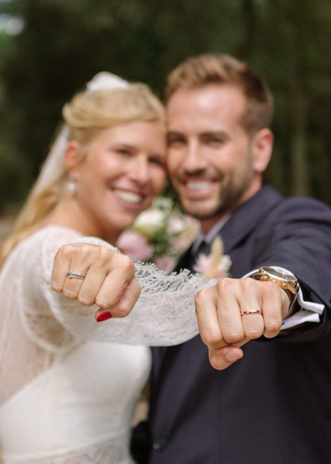 Pareja recién casada enseña sus anillos a cámara